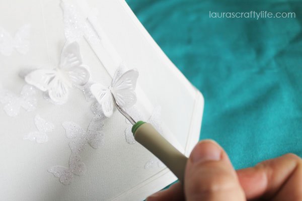 Use weeding tool to add butterflies to lampshade with hot glue