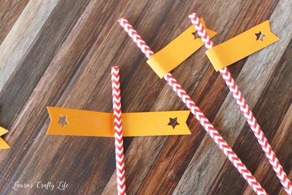 Use adhesive to attach straw flags to paper straws